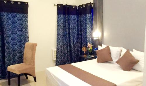 a bedroom with a bed and a chair and curtains at My Dream Place Hotel - Near Robinsons Mall in Butuan
