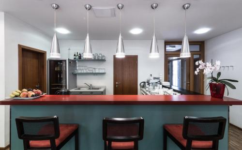 a kitchen with a red counter and some chairs at Penzion Palouček in Prague
