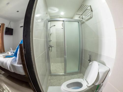 uma casa de banho com um chuveiro e um WC com um espelho. em Blue Ribbon Dive Resort em Mabini
