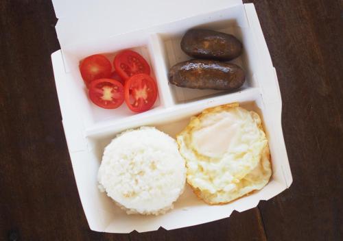Una lonchera con arroz, tomates y donas. en Balay Travel Lodge, en Paoay