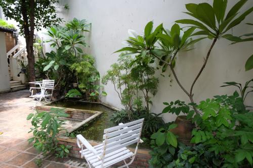 a patio with white chairs and trees and plants at Moon house tropical garden - West side in Nha Trang