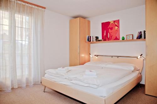 a white bed in a room with a window at Apartment Saphir 2 - GRIWA RENT AG in Grindelwald