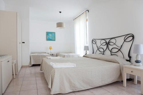 a white bedroom with a large bed and two tables at Hotel Amarea - Aeolian Charme in Canneto