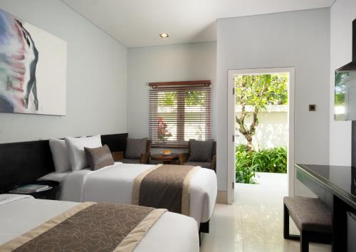 a hotel room with two beds and a couch at The Village Home in Sanur