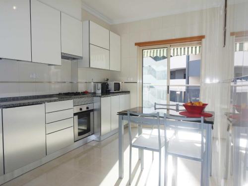 ラゴスにあるC05 - Convento Apartmentの白いキャビネットとガラスのテーブル付きのキッチン