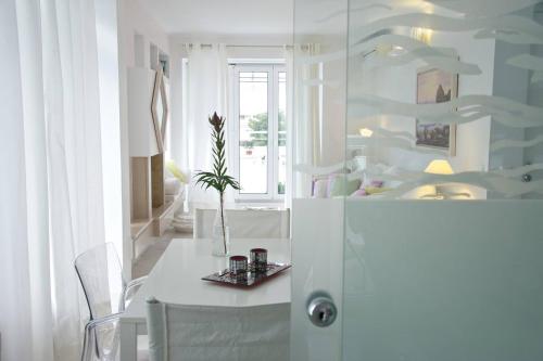 um quarto branco com uma mesa e um vaso com uma planta em Sea View Dreamy Penthouse in Vouliagmeni em Atenas