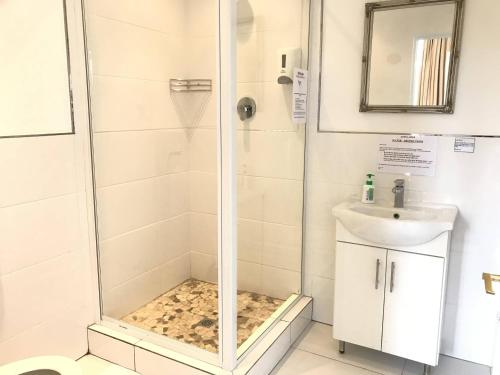a shower with a glass door next to a sink at Altona Lodge in Cape Town