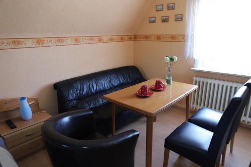 ein Wohnzimmer mit einem Tisch, Stühlen und einem Sofa in der Unterkunft Ferienwohnung Deichgraf in Westerland