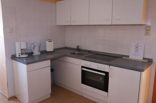 eine kleine Küche mit weißen Schränken und einem Waschbecken in der Unterkunft Ferienwohnung Deichgraf in Westerland