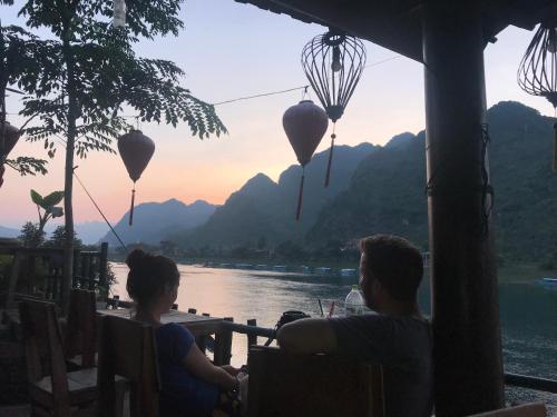 two people sitting at a table overlooking a river with balloons at Phong Nha Coco House in Phong Nha