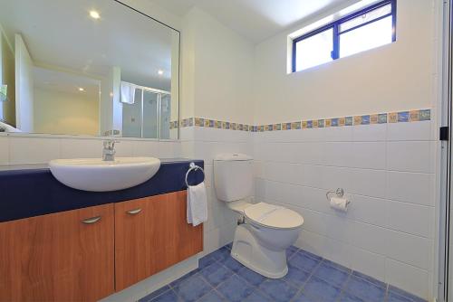 a bathroom with a sink and a toilet and a mirror at Kacy's Bargara Beach Motel in Bargara