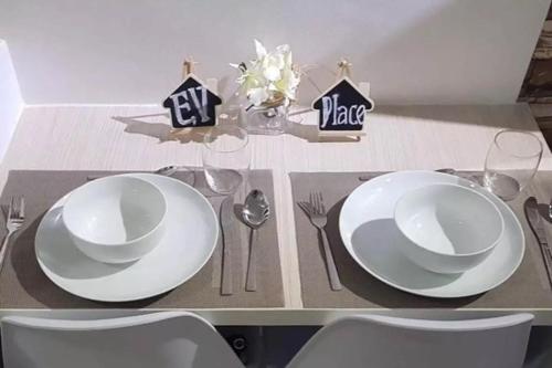 una mesa con dos platos blancos y cubiertos en EV Place, en Manila