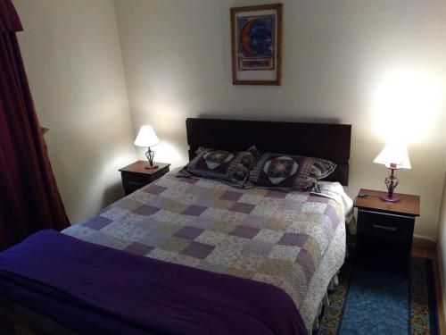 a bedroom with a bed with two lamps on tables at Cabaña la villa in Frutillar