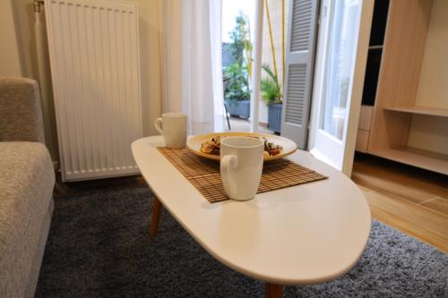 a white table with a bowl and two cups on it at Studio Posh with garden in Kolonaki in Athens
