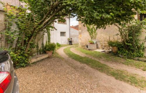 a road leading to a house with a person walking down it at Le Gîte du Lavoir in Marzy
