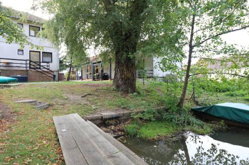 a tree next to a river with a wooden bridge at Spreewaldhotel Garni Raddusch in Vetschau