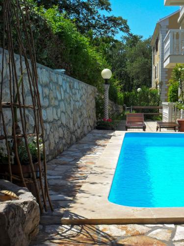 a swimming pool in a yard with a stone wall at Apartments and Rooms Degra in Umag