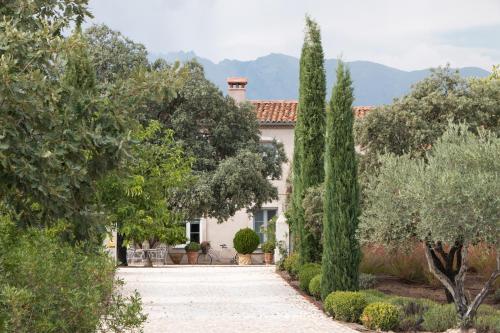 a house with a garden with trees and a driveway at La Casa de los Tomillares in Candeleda