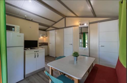 a small kitchen with a table and a refrigerator at Camping Sènia Caballo de Mar in Pineda de Mar