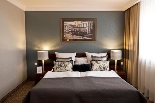 a bedroom with a large bed with two lamps at Hotel Tarnovia in Tarnów