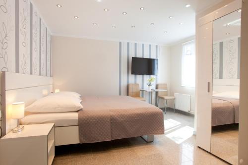 a white bedroom with two beds and a desk at Villa Natalia am See in Friedrichshafen