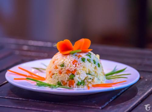 a plate with a rice ball with orange flowers on it at Gunbaru Inn in Ukulhas