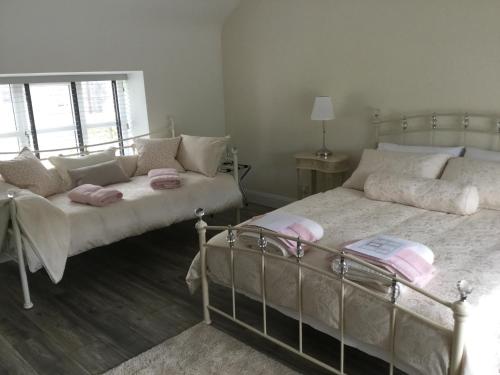 a bedroom with two beds with pink pillows at The Stone House, Multyfarnham in Multyfarnham