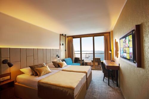 a hotel room with two beds and a desk at Grand Hotel Bernardin in Portorož