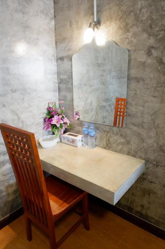 a table with a mirror and a chair and flowers at โรงแรมโทนี่วิลเลจTony Hotel in Phatthalung