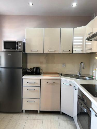 a kitchen with white cabinets and a stainless steel refrigerator at Apartamenty ALICJA in Dzierżoniów