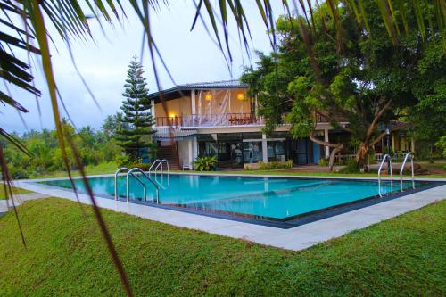 a swimming pool in front of a house at Nico Lagoon Hotel in Negombo