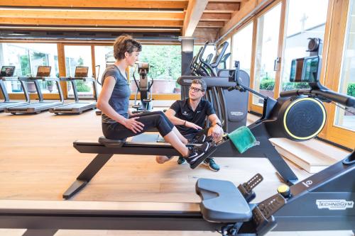 a woman and a man sitting on a treadmill in a gym at Wellnessresidenz Alpenrose in Maurach