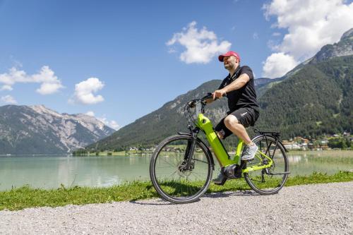 a man riding a bike next to a lake at Wellnessresidenz Alpenrose in Maurach