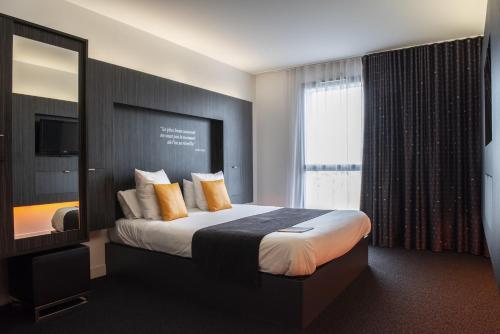 a hotel room with a bed and a large window at Akena Nantes Atlantis Zénith in Saint-Herblain