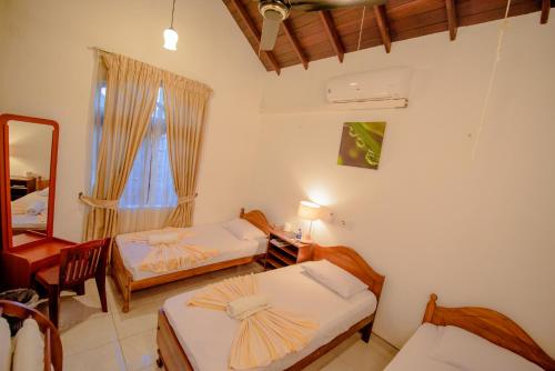 a room with two beds and a mirror and a window at Muhsin Villa - Galle Fort in Galle