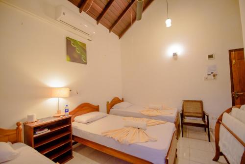 a bedroom with two beds and a desk and a chair at Muhsin Villa - Galle Fort in Galle