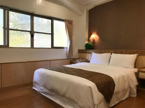 魚池鄉的住宿－名人飯店，一间卧室设有一张大床和一个窗户。