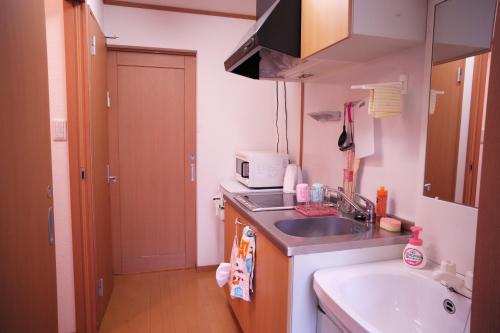 una pequeña cocina con fregadero y microondas en Takaraboshi room 301 Sannomiya 10 min en Kobe