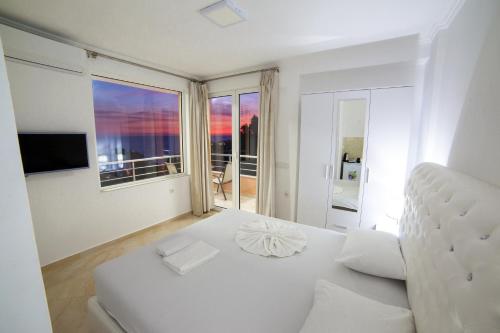 a white bedroom with a bed and a large window at Apartments Panorama Alaj in Ulcinj