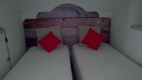 two beds in a small room with red pillows at Trulli in Valle D'Itria in Cisternino