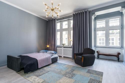 a bedroom with a bed and a chair and windows at Marzenie Starego Miasta in Gdańsk