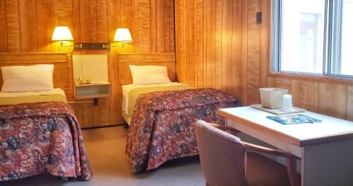 Habitación con 2 camas, mesa y escritorio. en Keystone Hotel, en Valdez