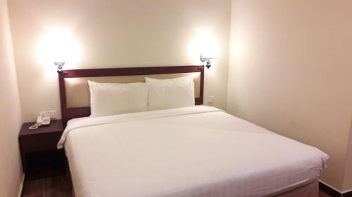 a bed in a hotel room with two lights on the wall at Cheng Ho Hotel in Malacca