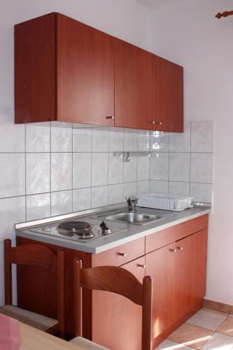 a kitchen with a sink and wooden cabinets at Budget Apartments Batkoski Pag in Pag
