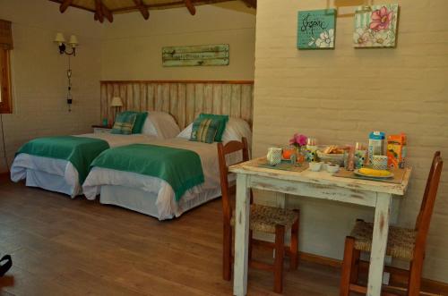 a bedroom with two beds and a table with a tableasonable at CABAÑA LA TOSCANA in Carmelo