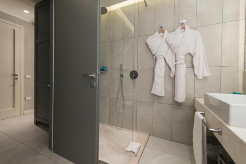 a bathroom with a shower and a sink and towels at Forte Village Resort - Pineta in Santa Margherita di Pula