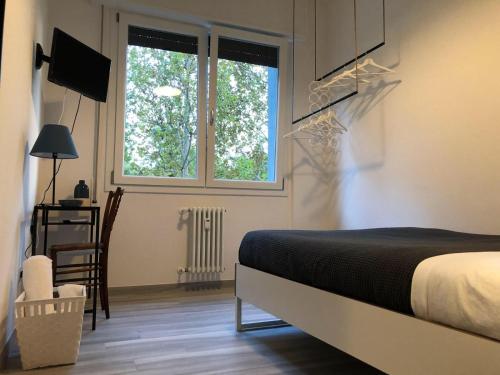 a bedroom with a bed and a desk and two windows at Four Rooms in Bologna