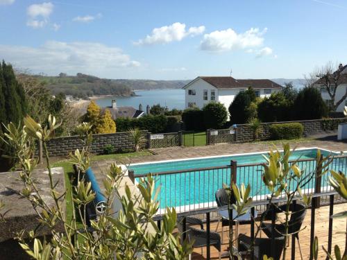 a swimming pool with a view of a house and a lake at Merlewood Hotel in Saundersfoot