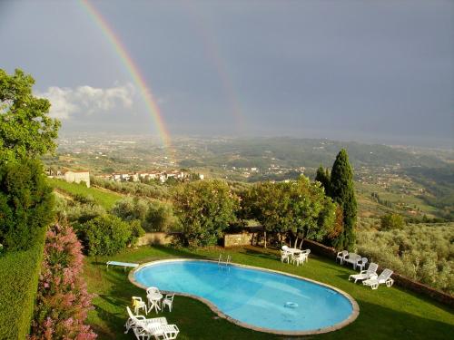 un arcobaleno sopra una piscina con tavolo e sedie di Fattoria Gambaro di Petrognano a Collodi