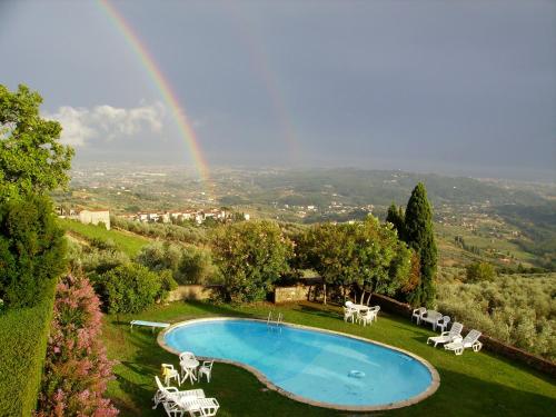 a rainbow over a swimming pool with a table and chairs at Fattoria Gambaro di Petrognano in Collodi